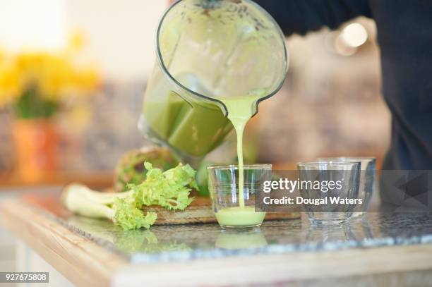 pouring a fresh smoothie drink in kitchen. - bleekselderij stockfoto's en -beelden