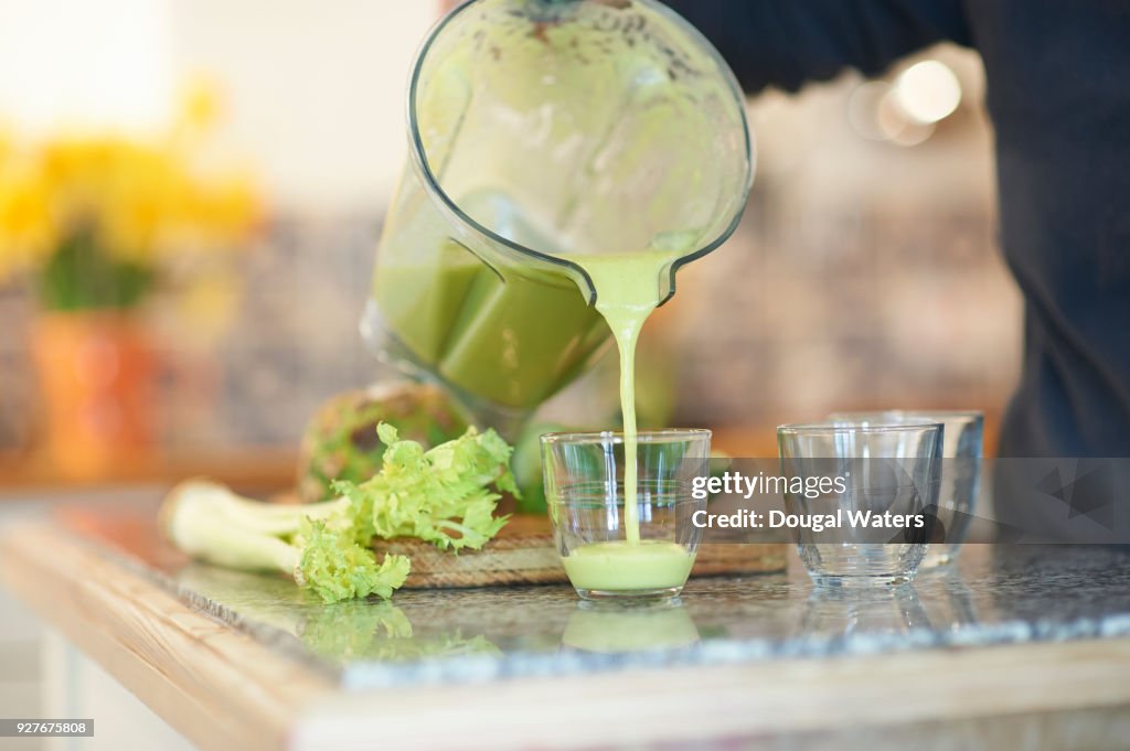 Pouring a fresh smoothie drink in kitchen.