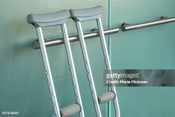 pair of metal crutches leaning against a modern steel handle on a glass door. - orthopaedic equipment imagens e fotografias de stock