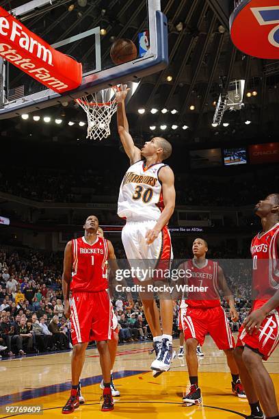 Stephen Curry of the Golden State Warriors shoots a jump layup against Trevor Ariza, Kyle Lowry and Aaron Brooks of the Houston Rockets during the...