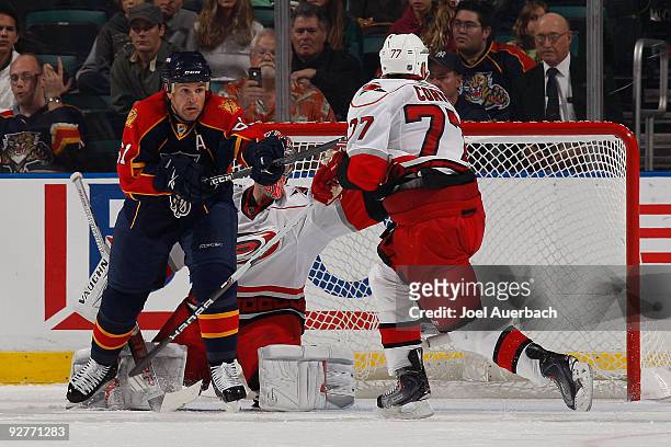 Cory Stillman of the Florida Panthers attempts to tip in the puck while being defended by Joe Corvo in front of goaltender Cam Ward of the Carolina...