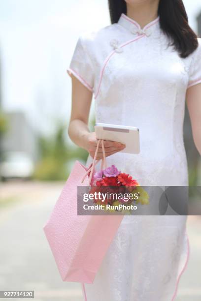 woman in cheongsam holing digital tablet and shopping bags outdoors - holing ipad stock pictures, royalty-free photos & images