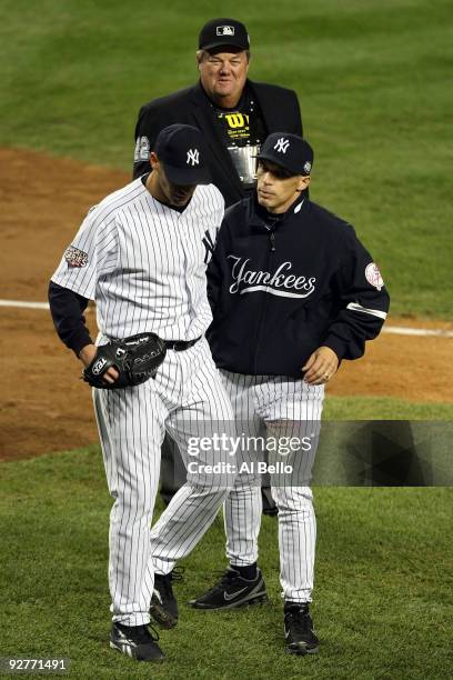 Starting pitcher Andy Pettitte of the New York Yankees is held back by manager Joe Girardi as Pettitte argues with home plate umpire Joe West at the...