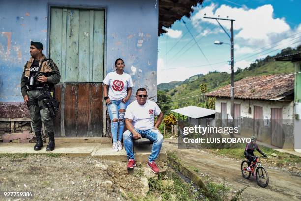 Police officer stands guards next to members of the Common Alternative Revolutionary Force political party, during a campaign rally for the upcoming...