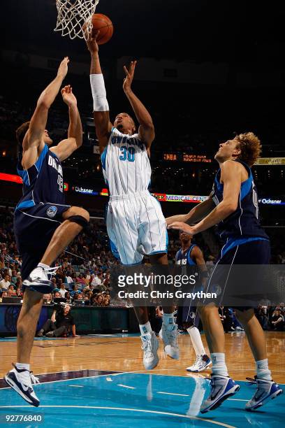 David West of the New Orleans Hornets makes a shot over Kris Humphries and Dirk Nowitzki of the Dallas Mavericks at New Orleans Arena on November 4,...