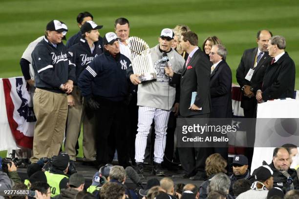 Manager Joe Girardi of the New York Yankees is interviewed as he celebrates with the trophy after their 7-3 win against the Philadelphia Phillies in...