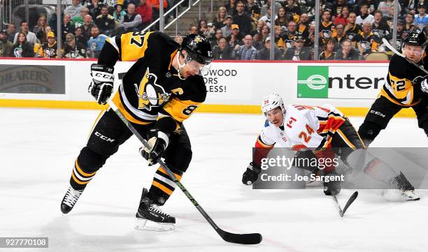 Sidney Crosby of the Pittsburgh Penguins handles the puck against Travis Hamonic of the Calgary Flames at PPG Paints Arena on March 5, 2018 in...