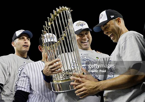 Andy Pettitte, Jorge Posada, Derek Jeter and Mariano Rivera of the New York Yankees celebrate with the trophy after their 7-3 win against the...