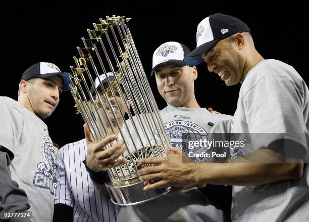Andy Pettitte, Jorge Posada, Derek Jeter and Mariano Rivera of the New York Yankees celebrate with the trophy after their 7-3 win against the...