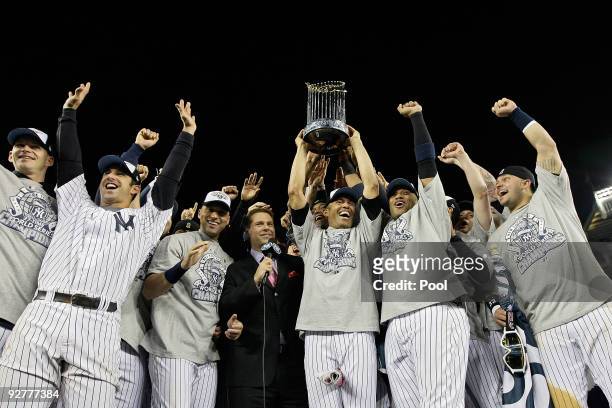 Mariano Rivera of the New York Yankees holds the trophy as he celebrates with Derek Jeter, Jorge Posada and other teammates celebrates with the...