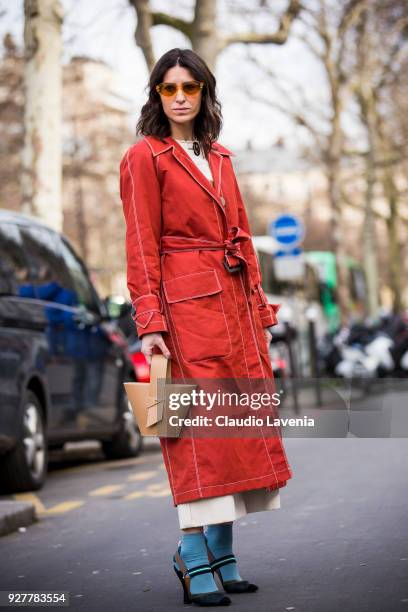 Deborah Reyner Sebag, wearing a red trench, is seen in the streets of Paris before the Giambattista Valli show during Paris Fashion Week Womenswear...