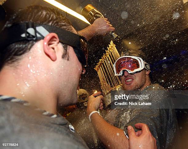 Phil Hughes and Joba Chamberlain of the New York Yankees celebrate with the trophy in the locker room after their 7-3 win against the Philadelphia...