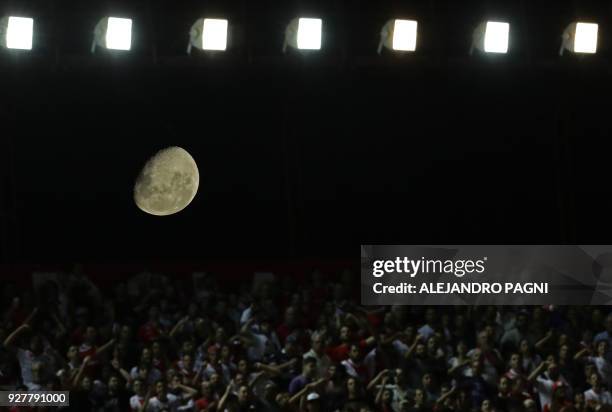 The moon is seen behind supporters of Argentinos Juniors during the Argentina First Division Superliga football match against Boca Juniors at the...