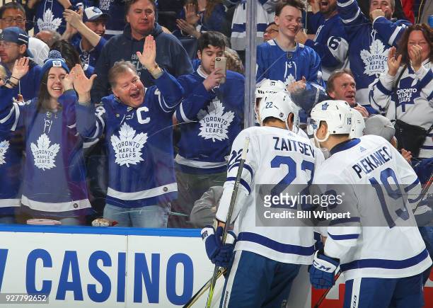 Leo Komarov of the Toronto Maple Leafs celebrates his second period goal with fans and teammates Nikita Zaitsev and Tomas Plekanec during an NHL game...