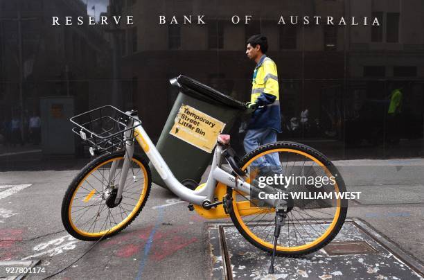 Man walks past the Reserve Bank of Australia building in Sydney on March 6 as Australia's central bank kept interest rates at a record in a widely...