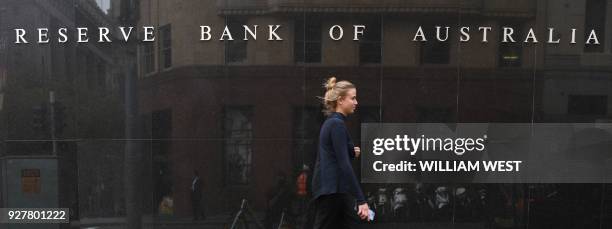 People walk past the Reserve Bank of Australia building in Sydney on March 6 as Australia's central bank kept interest rates at a record in a widely...