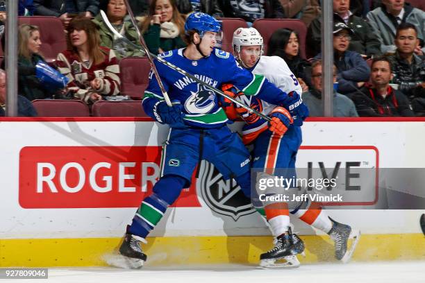 Ben Hutton of the Vancouver Canucks checks Johnny Boychuk of the New York Islanders during their NHL game at Rogers Arena March 5, 2018 in Vancouver,...