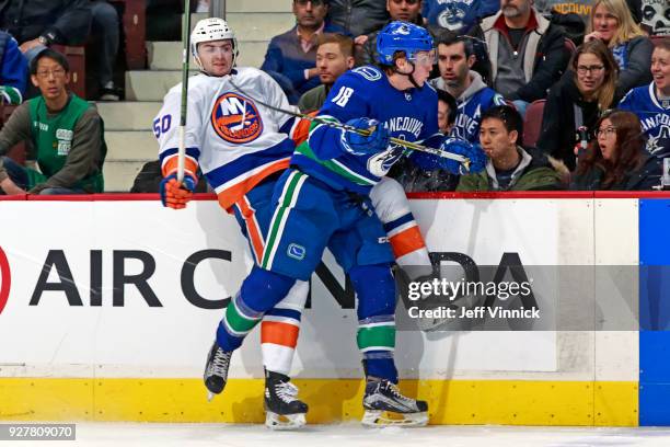 Jake Virtanen of the Vancouver Canucks checks Adam Pelech of the New York Islanders during their NHL game at Rogers Arena March 5, 2018 in Vancouver,...