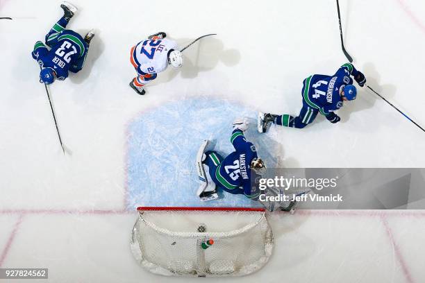 Anders Lee of the New York Islanders looks on as teammate Jordan Eberle scores against Jacob Markstrom of the Vancouver Canucks during their NHL game...