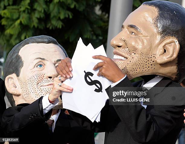 Members of anty-poverty group Oxfam wearing masks of world leaders French President Nicolas Sarkozy and US President Barack Obama move paper money...