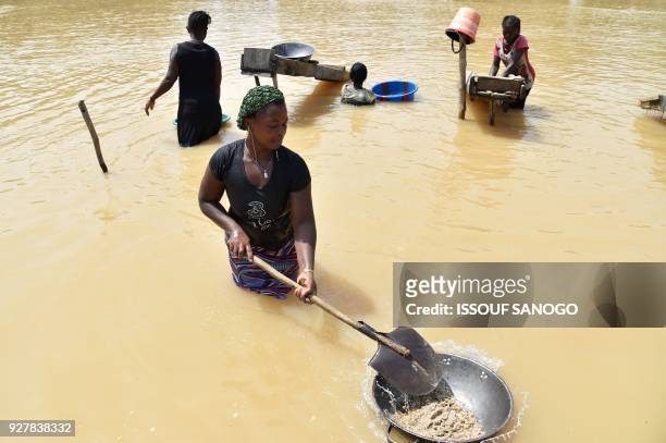 Women gold prospectors work in the Pampana river on March 5, 2018 near Mekeni, northern Sierra Leone. - Down a dirt road that slopes off a bridge,...