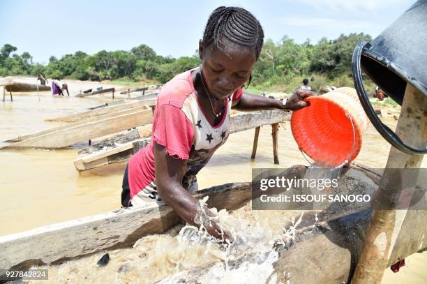 Women gold prospectors work in the Pampana river on March 5, 2018 near Mekeni, northern Sierra Leone. - Down a dirt road that slopes off a bridge,...