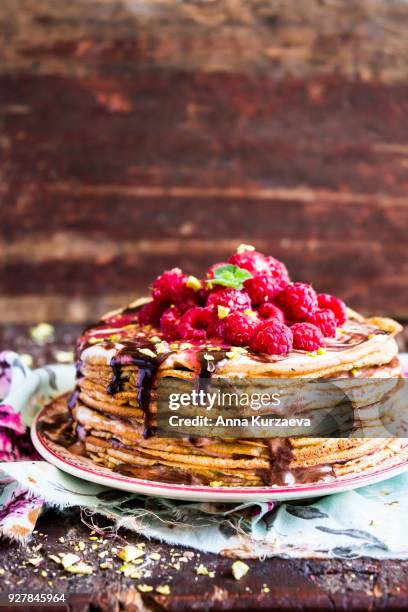 stack of wheat golden pancakes or pancake cake with freshly picked raspberry, chopped pistachios, chocolate sauce on a dessert plate, selective focus - freshers week stock pictures, royalty-free photos & images