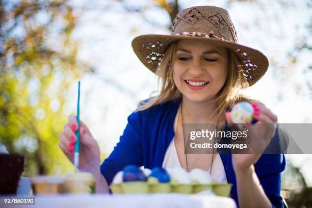 smiling young woman decorating easter eggs outdoors on a sunny day - decoupage stock pictures, royalty-free photos & images