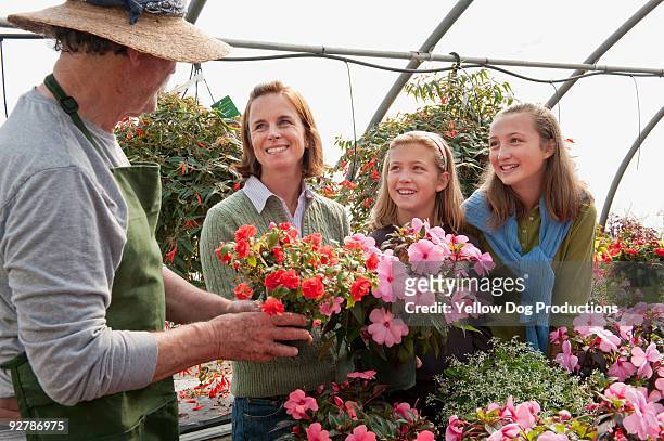 garden center worker helping family in greenhouse - manchester vermont foto e immagini stock