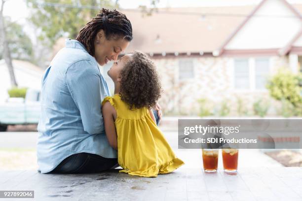 moeder en jonge dochter genieten van elkaar buiten zitten - back porch stockfoto's en -beelden