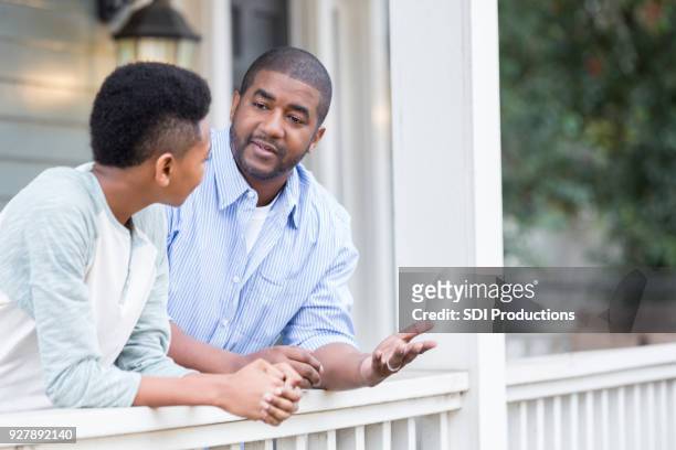 vader en zoon in ernstige veranda gesprek - child standing talking stockfoto's en -beelden