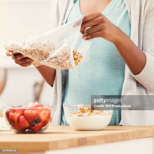 unrecognizable woman pours breakfast cereal with fruit - eating fiber stock pictures, royalty-free photos & images