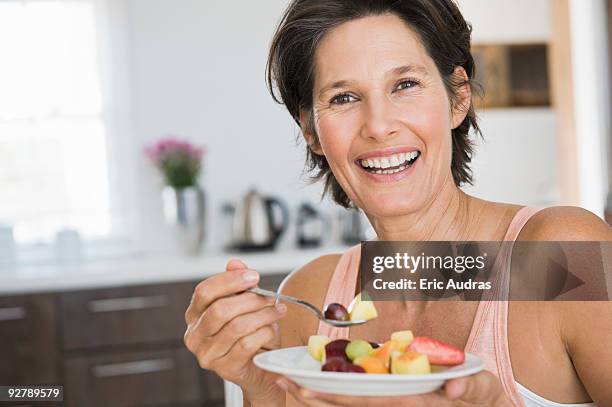 woman eating fruit salad - woman eating fruit stock pictures, royalty-free photos & images