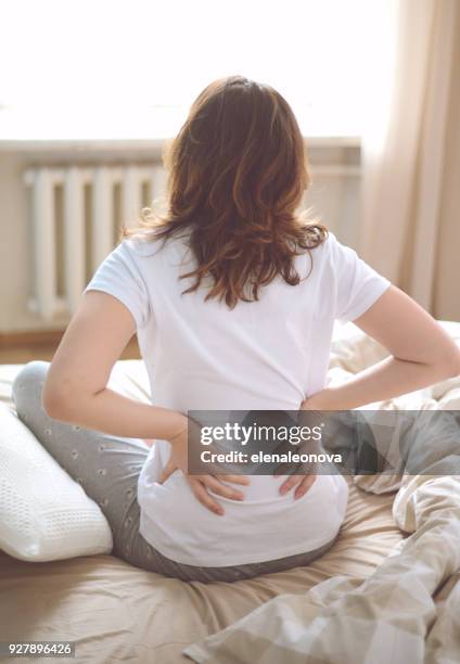 unhappy young women in the bedroom - back pain bed stock pictures, royalty-free photos & images