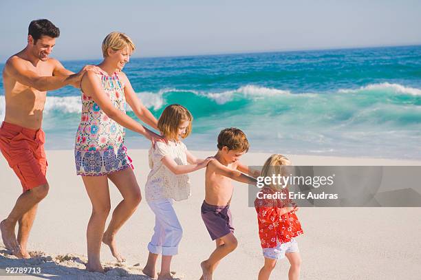 family walking on the beach in train formation - conga stock pictures, royalty-free photos & images