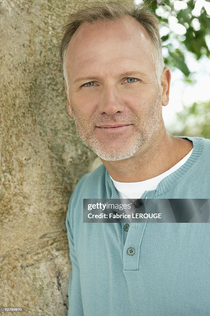 Man leaning against a tree trunk