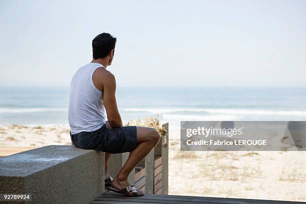 rear view of a man sitting on a boardwalk - tank top stock pictures, royalty-free photos & images