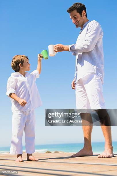 man and his son toasting with coffee cups on the beach - african africa child drinking water cup stock pictures, royalty-free photos & images