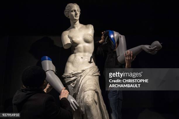 Men dismantle the symbolicly attached prosthetic arms from a replica of the Venus de Milo during an action led by Handicap International to raise...