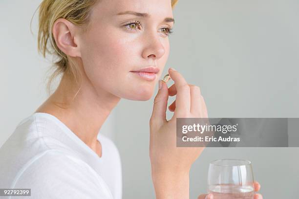 woman taking an omega-3 capsule - omega stock pictures, royalty-free photos & images