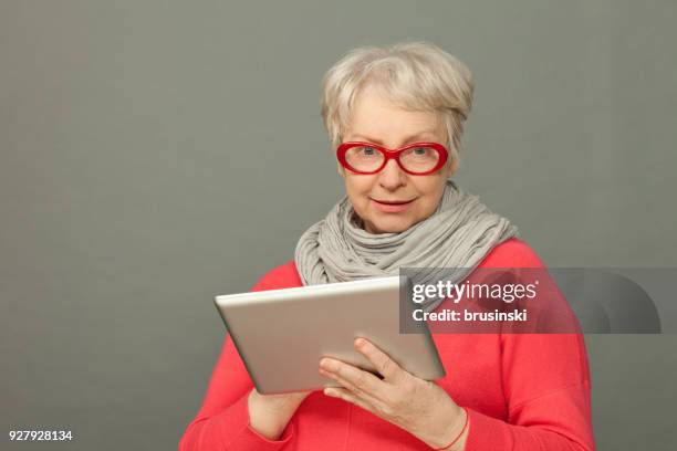 o retrato de estúdio closeup da mulher de 65 anos de idade sênior atraente usando o tablet - 65 69 years - fotografias e filmes do acervo