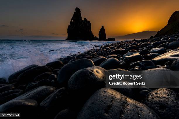 rock formation ribeira de janela at sunrise with black stones at the beach, porto moniz, madeira, portugal - janela stock-fotos und bilder