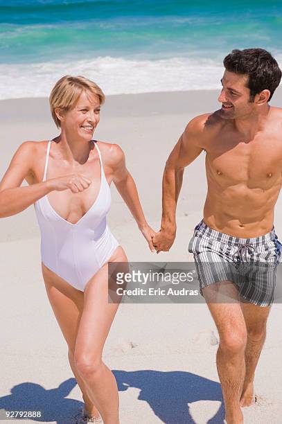 couple running on the beach - urlaub frau strand sonne blond kurze haare stock-fotos und bilder