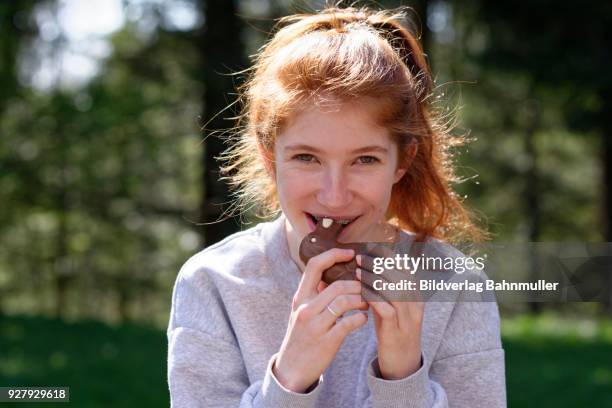 young girl with chocolate easter bunny, biting in easter bunny, easter, upper bavaria, bavaria, germany - easter bunny face stockfoto's en -beelden