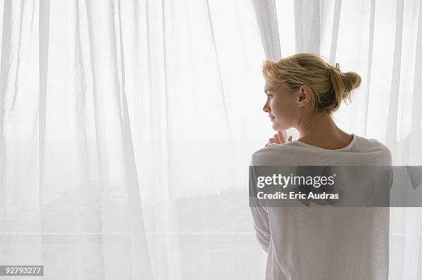 rear view of a woman opening the curtain of balcony - see thru nightgown - fotografias e filmes do acervo