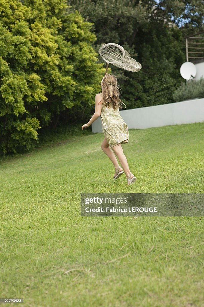 Girl playing with a butterfly net in a garden