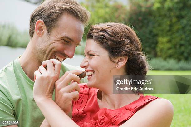 couple feeding chocolates to each other and smiling - couple chocolate stock-fotos und bilder