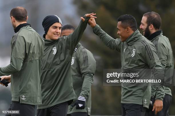 Juventus' Argentinian forward Paulo Dybala and Juventus' Brazilian defender Alex Sandro tap hands during a training session on the eve of the UEFA...