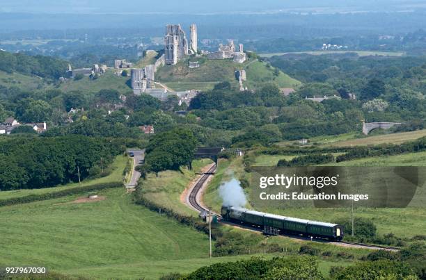 Steam train with a backdrop of Corfe Castle on the Swanage Railway in Dorset England UK.