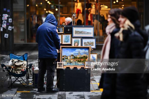 People take a look at different kinds of souvenirs at the Knez Mihailova Street in Belgrade, Serbia on March 04, 2018. The city has a different...
